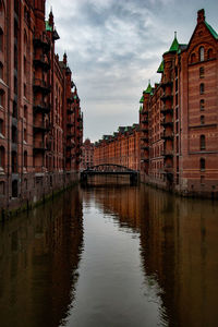 River amidst buildings in city against sky at dusk