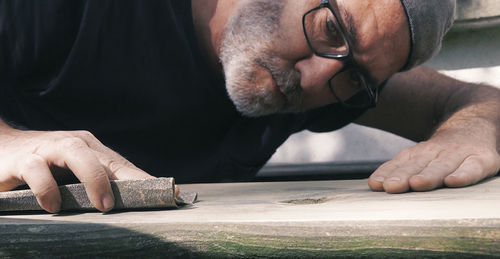 Close-up of male carpenter sanding wood in workshop