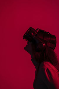 Woman using virtual reality headset against red background