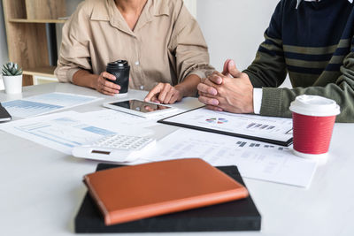 Midsection of business people working on table