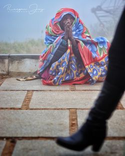 Low section of woman standing by multi colored umbrella