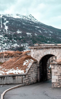 Arch bridge over snowcapped mountains against sky