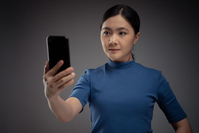 Portrait of mid adult man using smart phone against gray background