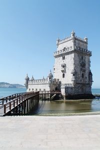 Building by sea against clear blue sky