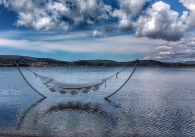 Hammock in lake against sky