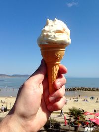 Close-up of hand holding ice cream against sea