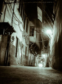 Empty alley amidst buildings in city at night