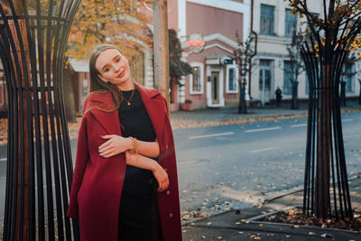 Portrait of smiling young woman standing in city