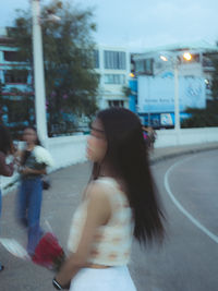 Side view of woman sitting on street at night