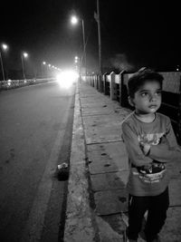 Portrait of boy standing on street at night