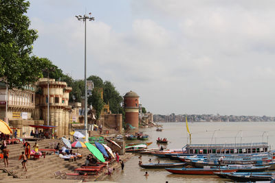 Sailboats moored in sea against buildings in city