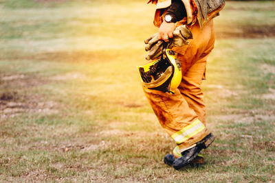 Low section of firefighter walking on field