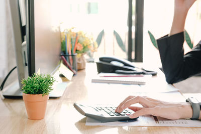 Midsection of woman using mobile phone on table