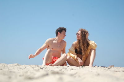 Young candid couple talking on a sandy beach 