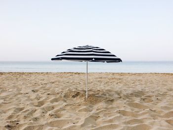 Sun umbrella on beach against clear sky