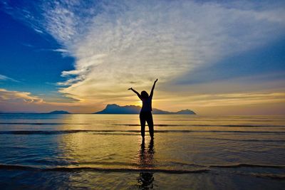 Silhouette person standing by sea against sky during sunset