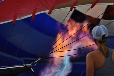 Rear view of woman standing by burning hot air balloon