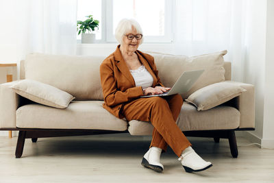 Young woman using laptop while sitting on sofa at home