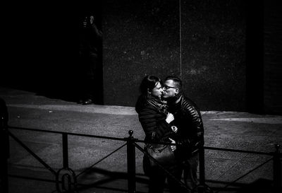 Man photographing while sitting on railing