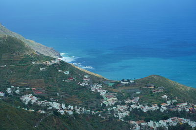 High angle view of buildings by sea against blue sky