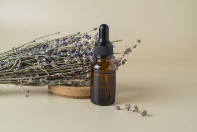 A face serum or oil in a brown droppwer bottle standing on a beige table background 