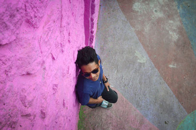 High angle view of man wearing sunglasses standing against wall