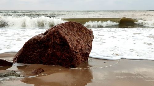 Rock formation on beach against sky