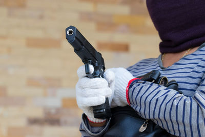Midsection of man holding gun and purse