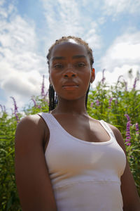 Portrait of young woman standing against plants