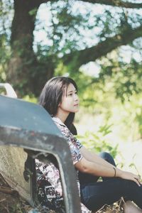 Young woman sitting in car against sky