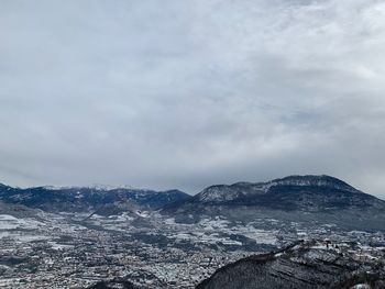 Aerial view of townscape by mountain against sky