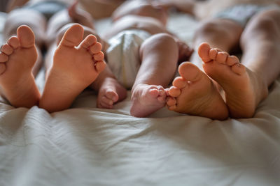 Newborn baby lays on bed between her siblings