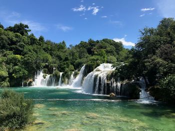 Scenic view of waterfall in forest against sky