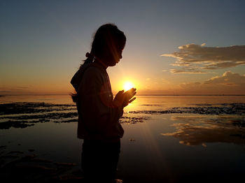 Man standing on beach against sky during sunset