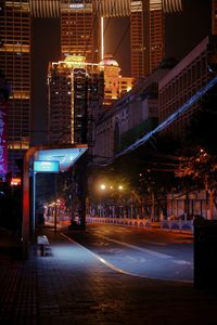 Illuminated street amidst buildings in city at night