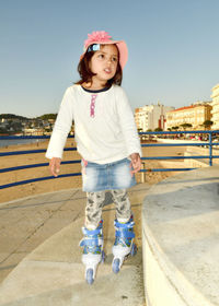 Portrait of happy girl standing on railing against clear sky