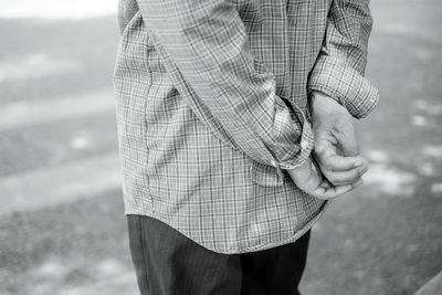 Midsection of man holding umbrella standing outdoors