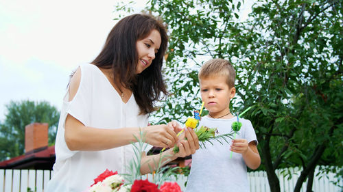 Summer, in the garden, slow motion, mom with a four-year-old son decorate the straw for juice. the