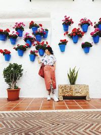 Rear view of person standing on potted plant against wall