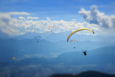 Low angle view of people paragliding against sky