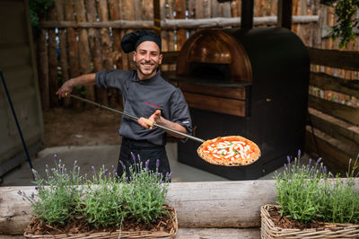 Pizzabaker getting fresh pizza out of the oven