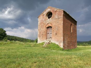 Old ruins of building on field against sky