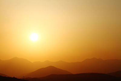 Scenic view of silhouette mountains against romantic sky at sunset