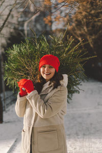 A beautiful girl in a red hat carries a christmas tree. christmas tree