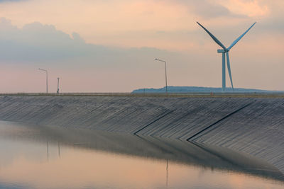 Wind turbines on landscape against sky during sunset