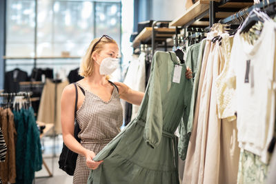 Mid adult woman wearing mask standing in clothing store