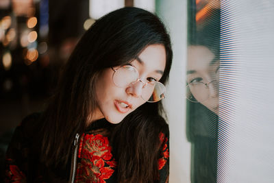 Portrait of young woman standing against illuminated city at night