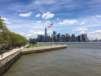 Scenic view of river by city against sky