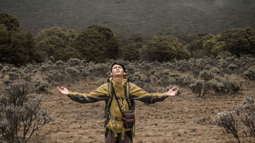 Full length of man with arms outstretched standing on land