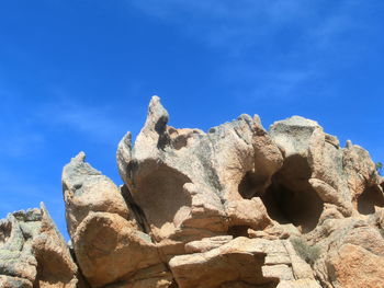 Low angle view of rocks against blue sky